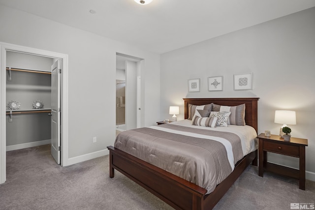 carpeted bedroom with a walk in closet, baseboards, and connected bathroom