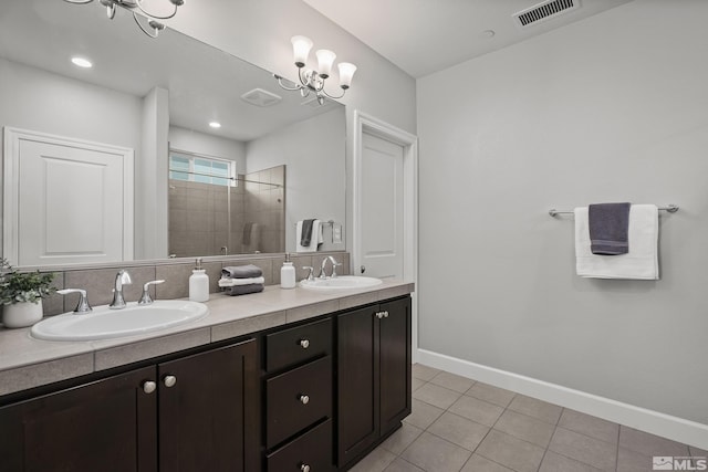 bathroom featuring tile patterned flooring, visible vents, a tile shower, and a sink