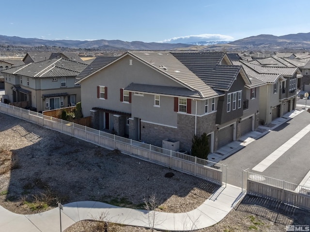 back of house featuring a mountain view, a garage, fence private yard, and a residential view