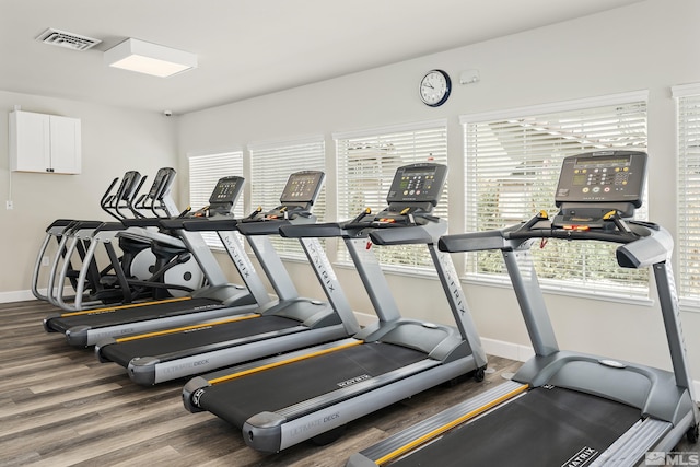 workout area with wood finished floors, visible vents, and baseboards