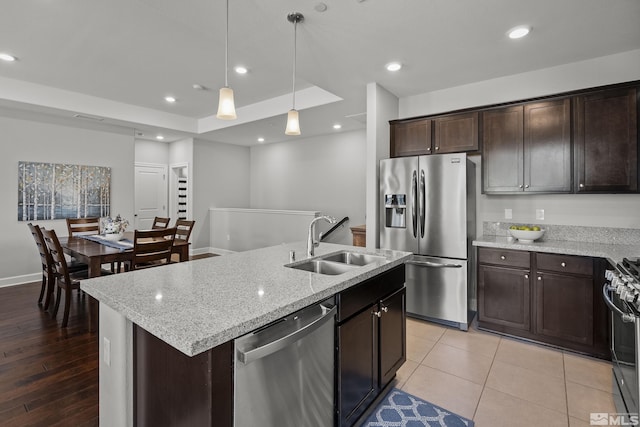 kitchen with dark brown cabinetry, recessed lighting, stainless steel appliances, a raised ceiling, and a sink