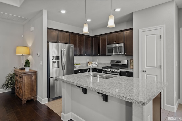 kitchen featuring a sink, dark brown cabinetry, light stone counters, and stainless steel appliances