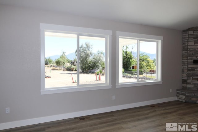 unfurnished living room featuring visible vents, baseboards, and wood finished floors