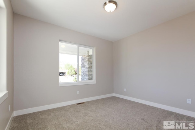 spare room featuring carpet flooring, baseboards, and visible vents