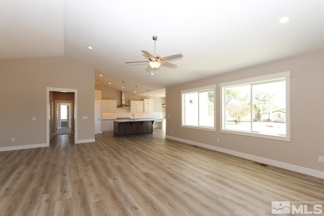 unfurnished living room featuring visible vents, a healthy amount of sunlight, ceiling fan, and light wood-style flooring