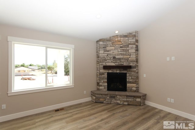 unfurnished living room featuring lofted ceiling, wood finished floors, a fireplace, and baseboards