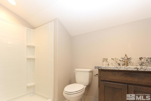 bathroom featuring toilet, a shower, baseboards, vanity, and vaulted ceiling