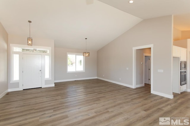 foyer entrance with baseboards, lofted ceiling, and wood finished floors