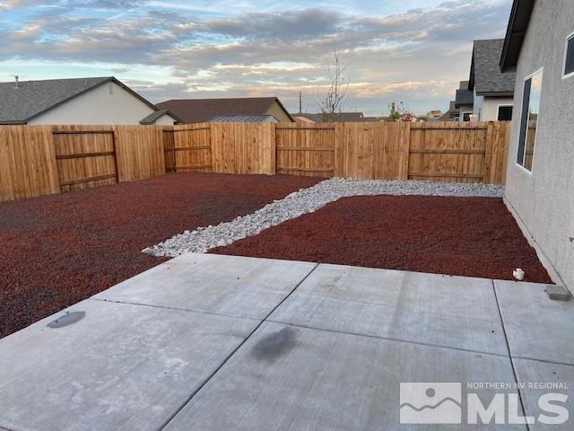 yard at dusk with a fenced backyard and a patio area