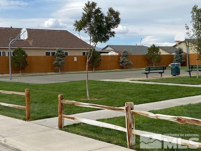 view of property's community featuring a lawn, community basketball court, and fence