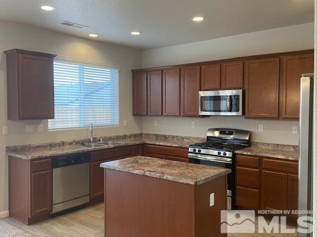 kitchen with a center island, dark stone counters, recessed lighting, appliances with stainless steel finishes, and a sink