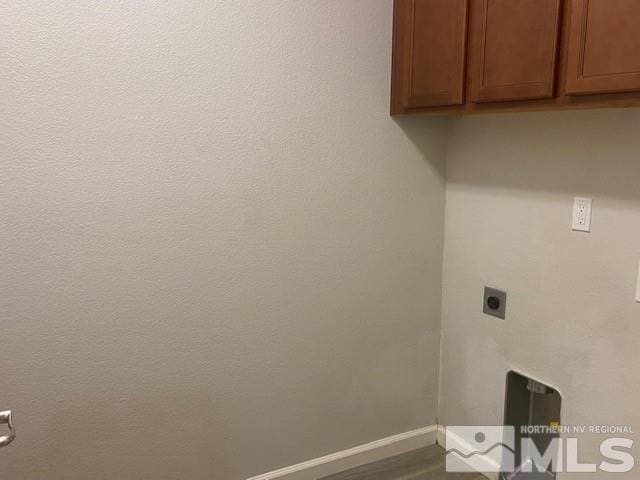 laundry room with electric dryer hookup, baseboards, and cabinet space