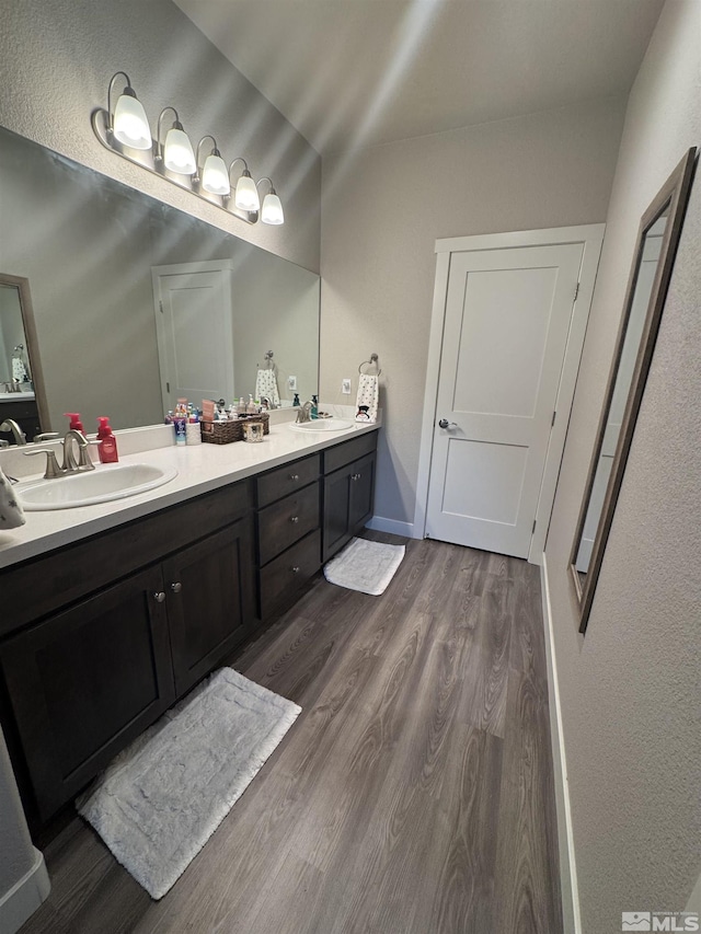 bathroom with a sink, wood finished floors, and double vanity