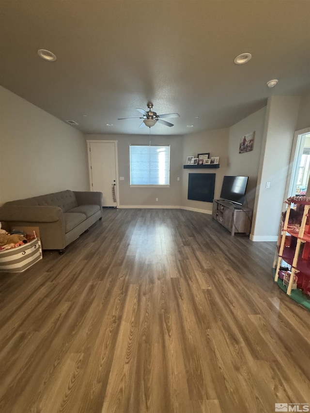 unfurnished living room featuring a ceiling fan, recessed lighting, wood finished floors, and baseboards