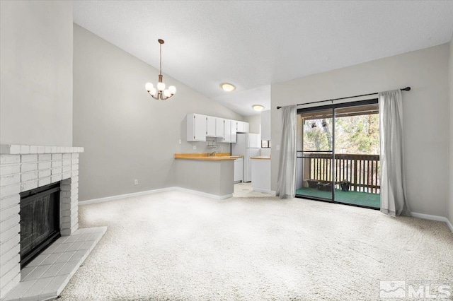 unfurnished living room featuring lofted ceiling, a textured ceiling, baseboards, a brick fireplace, and a chandelier