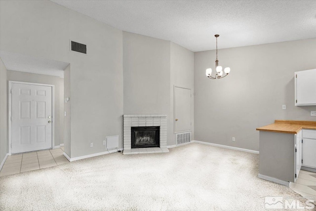 unfurnished living room with visible vents, a notable chandelier, high vaulted ceiling, a textured ceiling, and baseboards