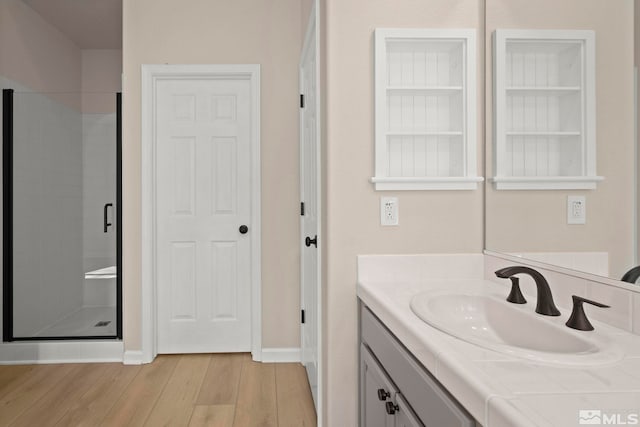 bathroom with a shower stall, vanity, baseboards, and wood finished floors