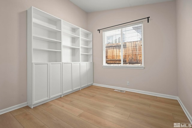 empty room with light wood-type flooring, baseboards, and visible vents