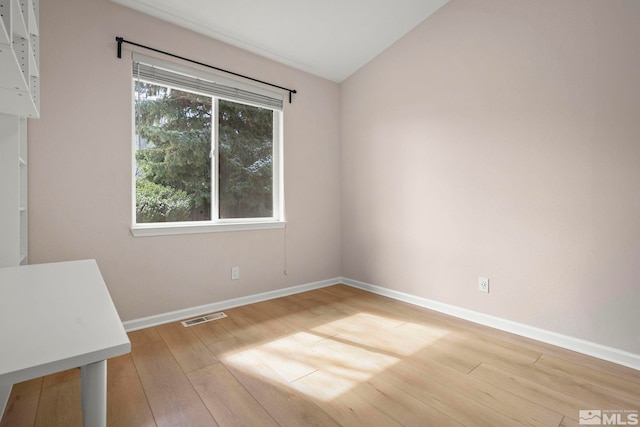 unfurnished room featuring vaulted ceiling, visible vents, baseboards, and wood finished floors