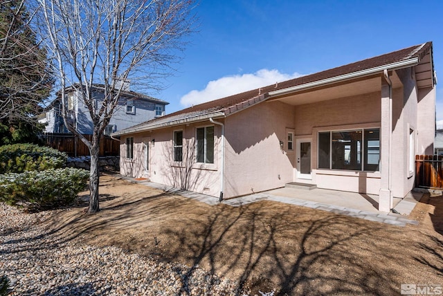 rear view of property featuring stucco siding, a patio, and fence