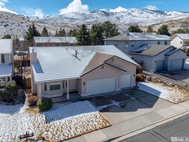 view of front facade with stucco siding, a mountain view, driveway, and a garage