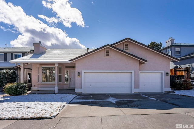 view of front facade with stucco siding, a tiled roof, concrete driveway, and a garage