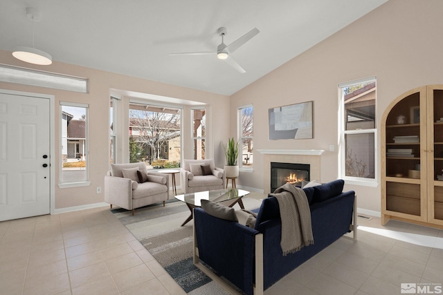 living room featuring baseboards, vaulted ceiling, tile patterned floors, a glass covered fireplace, and a ceiling fan