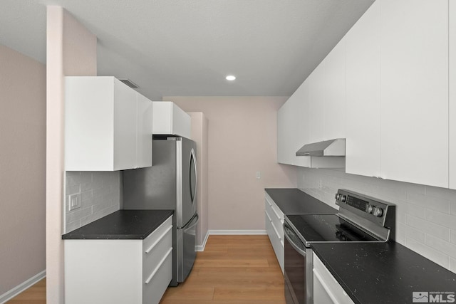 kitchen with dark countertops, ventilation hood, white cabinets, and appliances with stainless steel finishes