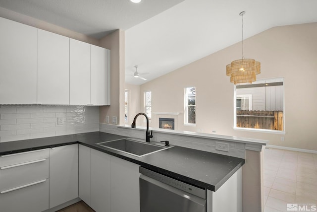 kitchen with dark countertops, dishwasher, a peninsula, and a sink