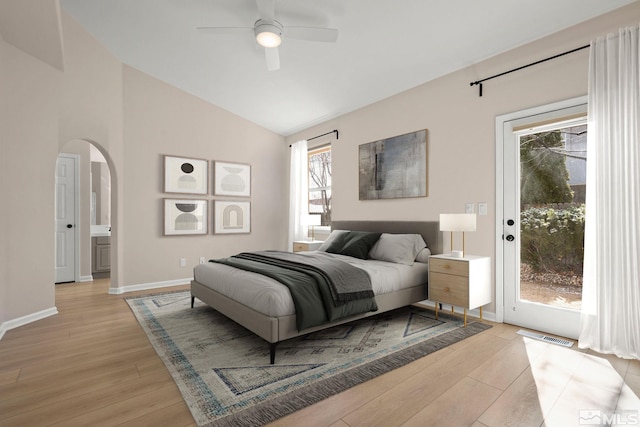 bedroom with lofted ceiling, access to outside, arched walkways, light wood finished floors, and baseboards