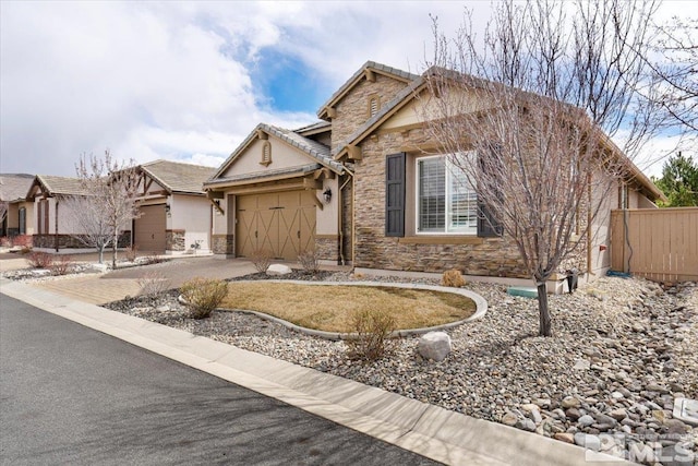 single story home featuring concrete driveway, a garage, fence, and stone siding