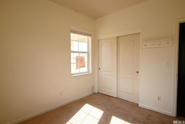 unfurnished bedroom with a closet, carpet floors, and baseboards