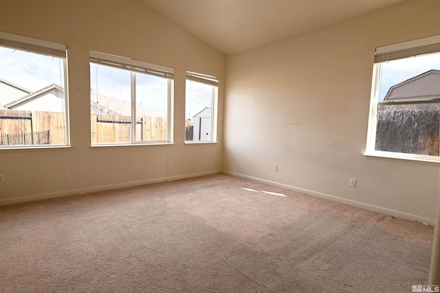 carpeted spare room featuring baseboards and vaulted ceiling