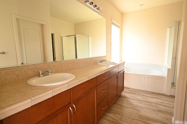 bathroom featuring a shower stall, a garden tub, double vanity, and a sink