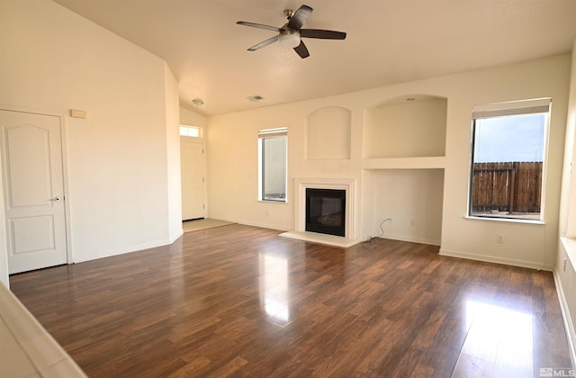 unfurnished living room featuring visible vents, a ceiling fan, a glass covered fireplace, dark wood-style flooring, and vaulted ceiling