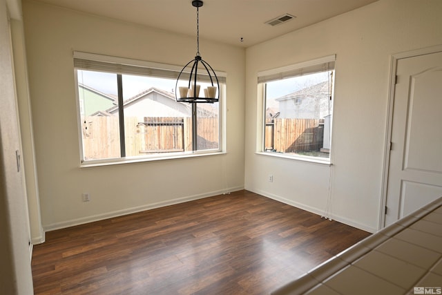 unfurnished dining area featuring dark wood-style floors, a notable chandelier, a healthy amount of sunlight, and visible vents