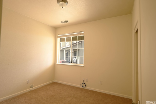 spare room with baseboards, light carpet, and visible vents