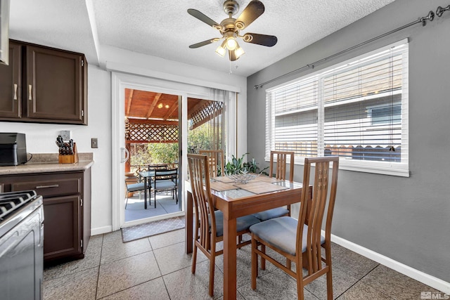 dining area featuring ceiling fan, baseboards, and a textured ceiling