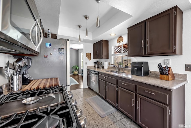 kitchen featuring a sink, hanging light fixtures, dark brown cabinetry, stainless steel appliances, and a raised ceiling