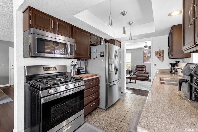 kitchen with a ceiling fan, a tray ceiling, light countertops, and stainless steel appliances