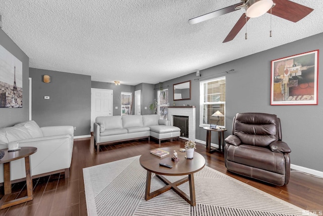 living room with a brick fireplace, wood finished floors, baseboards, and ceiling fan