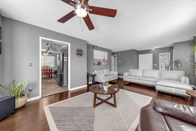 living area with baseboards, a textured ceiling, wood finished floors, and a ceiling fan