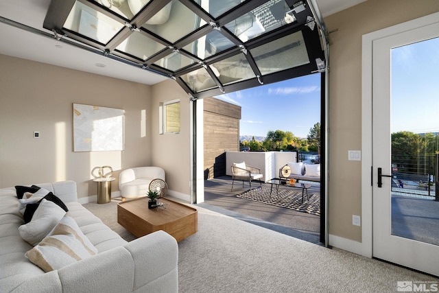 living area featuring a wealth of natural light, baseboards, and carpet floors