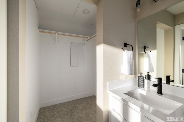 bathroom featuring a spacious closet, vanity, and baseboards