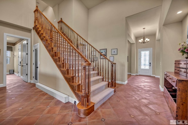 tiled entryway featuring baseboards, stairs, recessed lighting, a towering ceiling, and a notable chandelier