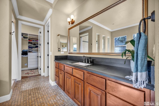 bathroom featuring a walk in closet, baseboards, vanity, and crown molding