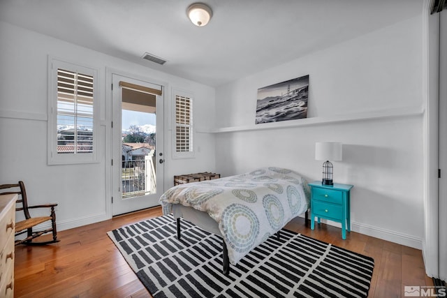 bedroom featuring hardwood / wood-style floors, access to exterior, baseboards, and visible vents