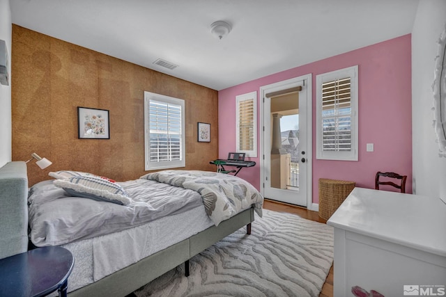 bedroom featuring access to exterior, wood finished floors, and visible vents