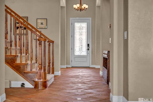 entrance foyer featuring baseboards, an inviting chandelier, and stairs