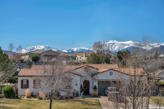 mediterranean / spanish-style home featuring stucco siding, a front lawn, a garage, a tiled roof, and a mountain view